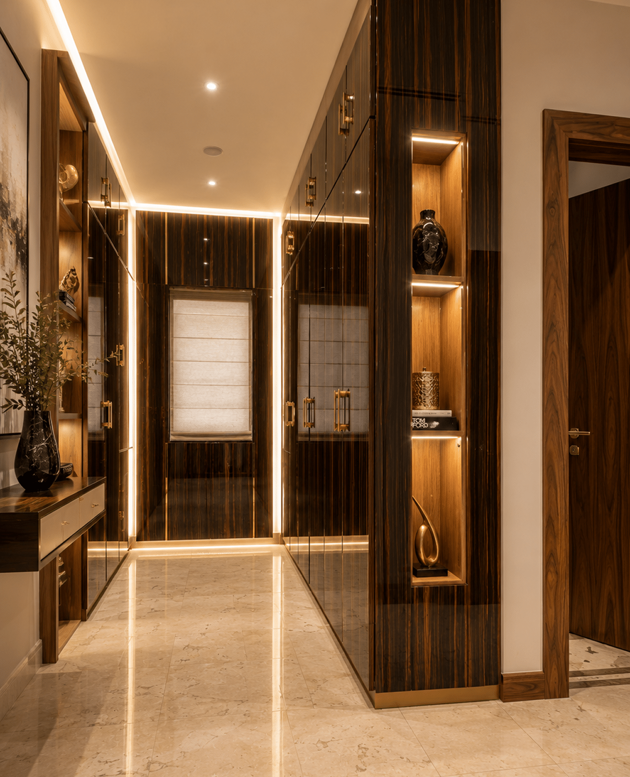 A luxurious hallway with dark wood paneled walls, illuminated shelves, and a light marble floor.